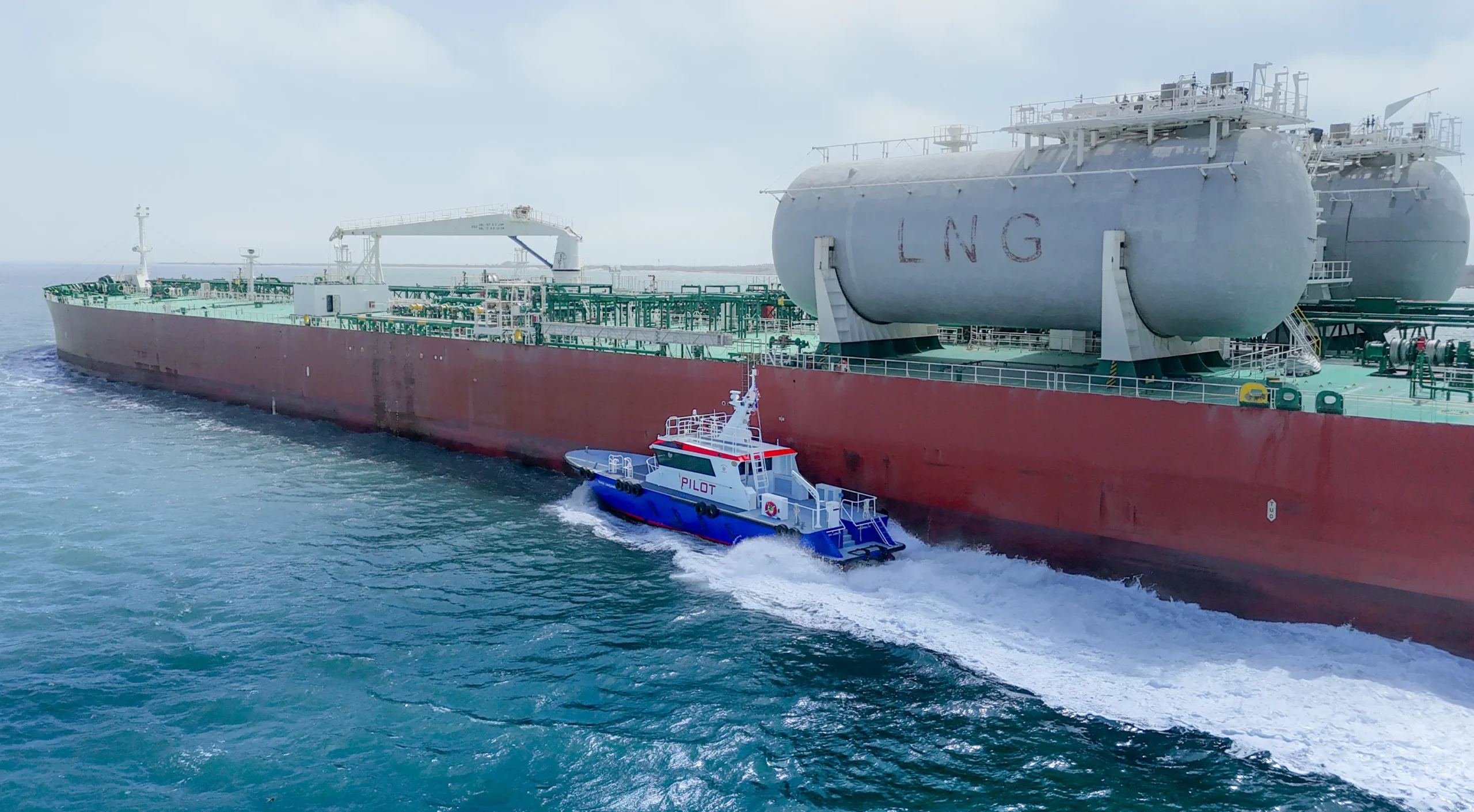 Aerial view of a pilot boat alongside an LNG tanker at sea